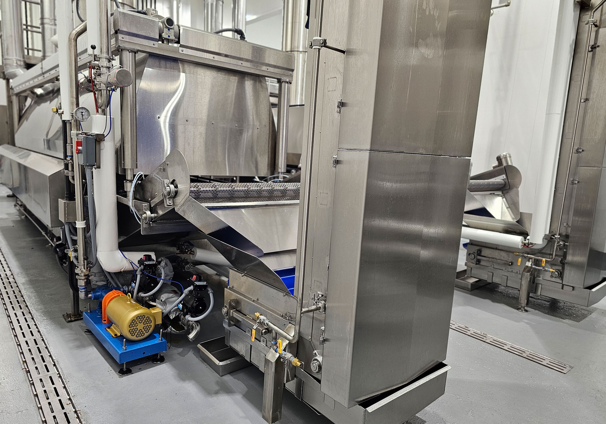 Side view of an installed JDM batch fryer and conveyor
